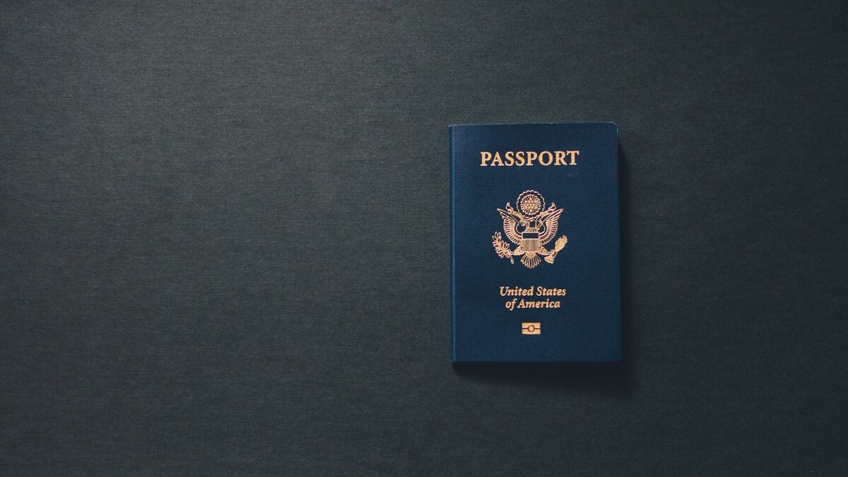 A single closed passport lying on a plain dark grey surface.