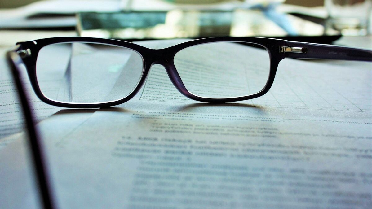 Reading glasses resting on a printed contract on a desk.