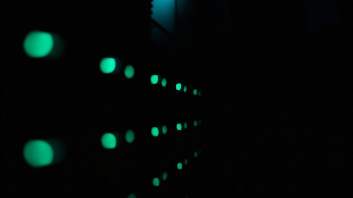 Abstract macro of a dark server rack with teal indicator lights at shallow depth of field.
